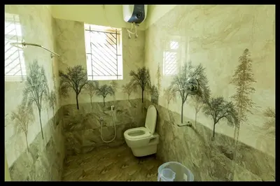 a bathroom with a toilet and trees on the wall at Serene Meadows Resort in Kāramadai