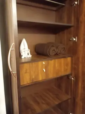 a wooden cabinet with a rolled up towel and towels at Padmam Service Apartments - 2BHK in Singānallūr