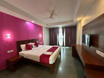 a bedroom with a large bed and a purple wall at CRYSTAL Inn in Kalpetta