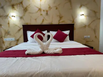 two white swans are towels on a bed at CRYSTAL Inn in Kalpetta