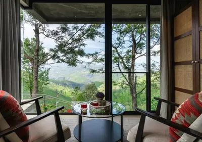 a room with a table and chairs and a large window at LohonoStays Amani Villa 10A in Coonoor