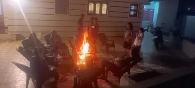 a group of people sitting around a fire at AJ Groups B&B Residency in Ooty