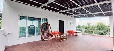 a room with red chairs and a table on a balcony at Nature stay Mysore in Mandya