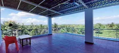 a balcony with two chairs and a table and a view at Nature stay Mysore in Mandya