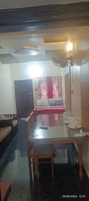a dining room with a table and a couch at Blue mount stay in Gūdalūr