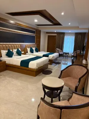 a hotel room with two beds and a table and chairs at Symphony in Ooty