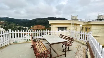 a table and two chairs sitting on a balcony at Away From Home - 4 - Rooms In Ooty, Home Stay Ooty in Ooty