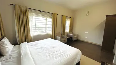 a bedroom with a white bed and a window at Away From Home - 4 - Rooms In Ooty, Home Stay Ooty in Ooty