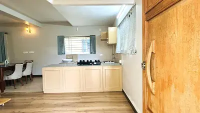 a kitchen with white cabinets and a counter top at Away From Home - 5 - Rooms In Ooty, Home Stay Ooty in Ooty