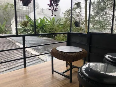 a room with a table and a stool on a balcony at Birdwing Cottage, Munnar in Munnar