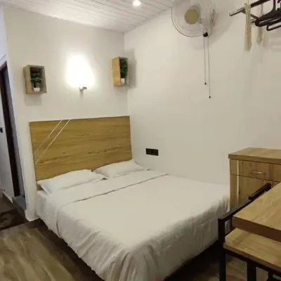 a white room with a bed and a table and a desk at Birdwing Cottage, Munnar in Munnar