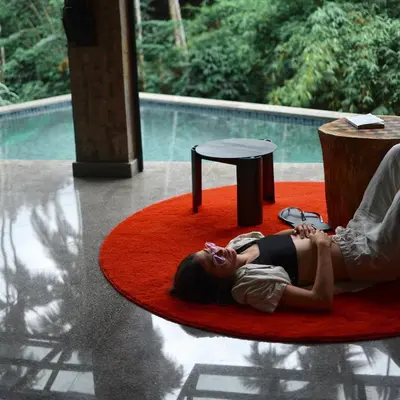 a woman laying on a red rug on a table at Bhadra - The Estate Villa in Wayanad