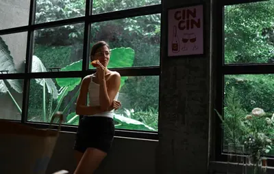 a woman brushing her teeth in front of a window at Bhadra - The Estate Villa in Wayanad