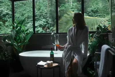 a woman sitting in a bath tub with a glass of wine at Bhadra - The Estate Villa in Wayanad