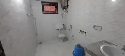 a white bathroom with a toilet and a sink at Janani Cottage in Ooty