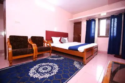 a bedroom with a bed and two chairs at Janani Cottage in Ooty