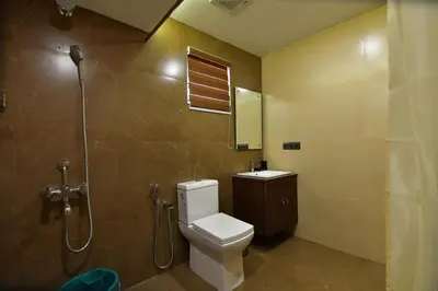 a bathroom with a toilet and a shower and a sink at The Garuda Hotels in Trichūr