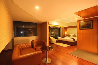 a room with a bed and a couch and a chair at The Garuda Hotels in Trichūr