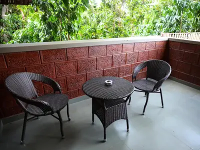 two chairs and a table on a balcony with a table and two chairs at Villa Katipadu Coorg in Srimangala