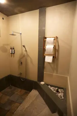 a bathroom with a shower and towels on a wall at Villa Katipadu Coorg in Srimangala