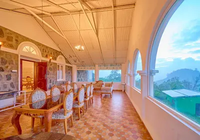 a room with chairs and a table and a large window at Emerald Stays Ooty By VOYE HOMES - Italian Luxury near Ooty Emerald Lake in Ooty