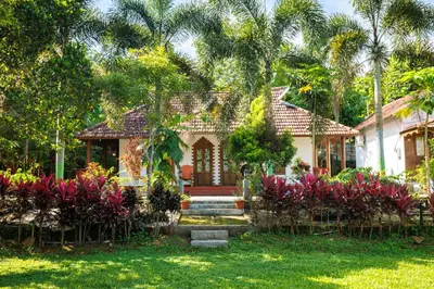 a house with palm trees and flowers in the yard at Birds Island Ayur-Yoga Retreat in Ernakulam