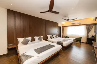 a hotel room with two beds and a ceiling fan at Hotel Mysore Radiance in Mysore