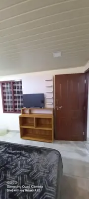 a room with a bed and a dresser and a door at Perumaal Homestay in Munnar