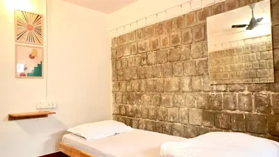 a bedroom with two beds and a brick wall at Roambay - Gokulam in Mysore