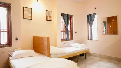 two beds in a room with two windows at Roambay - Gokulam in Mysore