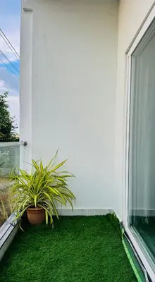 a balcony with green grass and a window at Stayover Homestay in Mysore