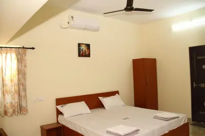 a bedroom with a bed with white sheets and a fan at Sapna residency in Mettuppālaiyam