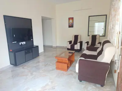 a living room with couches and a flat screen tv at Sapna residency in Mettuppālaiyam