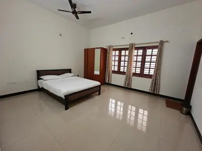 a bedroom with a bed and a ceiling fan at Emerald Luxury Villa in Mysore