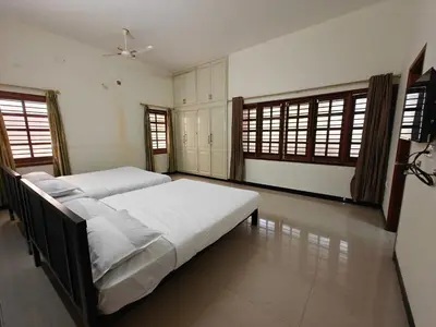 a bedroom with two beds and two windows at Emerald Luxury Villa in Mysore