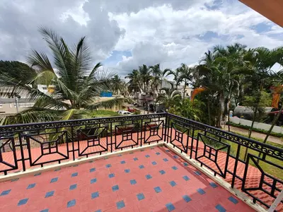 a balcony with tables and chairs and palm trees at Emerald Luxury Villa in Mysore