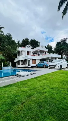a white house with two cars parked in front of it at Le Casabella in Kalpetta