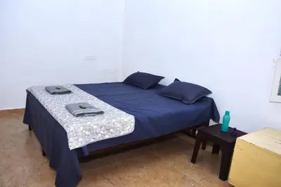 a bed with a blue comforter and a table at Beyond Ghatts Homestay in Dhali