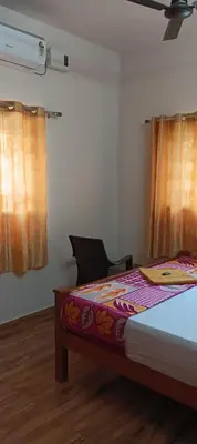 a bedroom with a bed and a chair and curtains at KPR Residency Near Isha - Adiyogi in Alāndurai