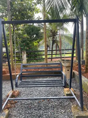 a swing seat in a park with palm trees at Scott legacy apartment in Kulattūr