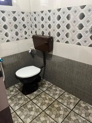a bathroom with a toilet in a tiled wall at Scott legacy in Kulattūr