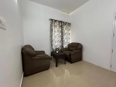 a living room with two chairs and a table at Puzhayoram Homestay in Trichūr
