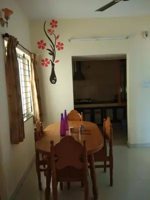 a dining room table and chairs with a flower on the wall at Gerones Residency Serviced Apartments & Home Stays in Coimbatore