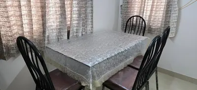 a dining room table with chairs and a table with a silver table cloth at PPH Living Arvind Inn in Coimbatore