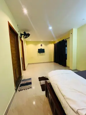 a bedroom with a large bed and a flat screen tv at familyvillasliesure in Padinjarathara