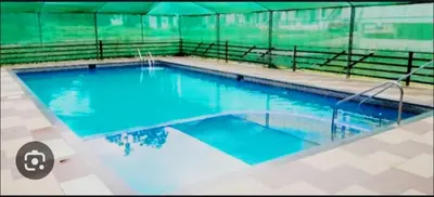 a large swimming pool with blue water in a building at Green Nest Villa at Athirappilly in Athirappilly