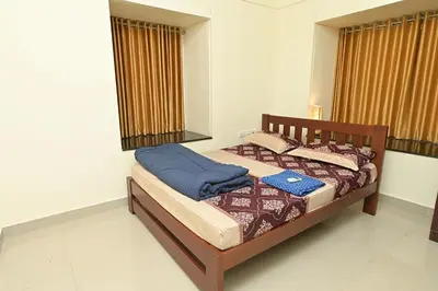 a bedroom with a bed with blue sheets at Gokulam By Upasana in Guruvāyūr