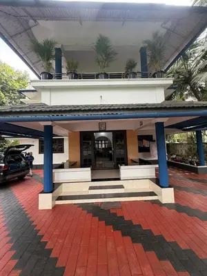 a building with blue columns and a parking lot at Dream House Near IIM Kozhikode & NIT Calicut in Kozhikode