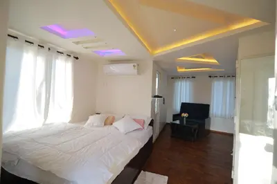 a bedroom with a bed with white sheets and windows at Blue Bell Resort in Periya