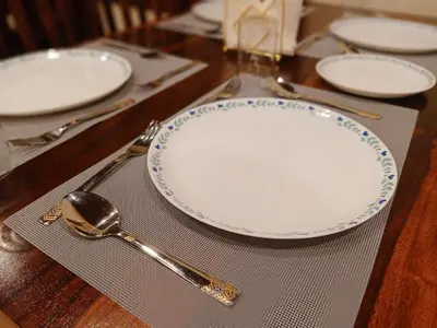 a table with an empty plate and spoons and forks at The Humming Bird A Stay Chapter in Ooty